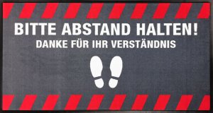 Fußmatte mit deutlichem Abstand-Halten-Hinweis