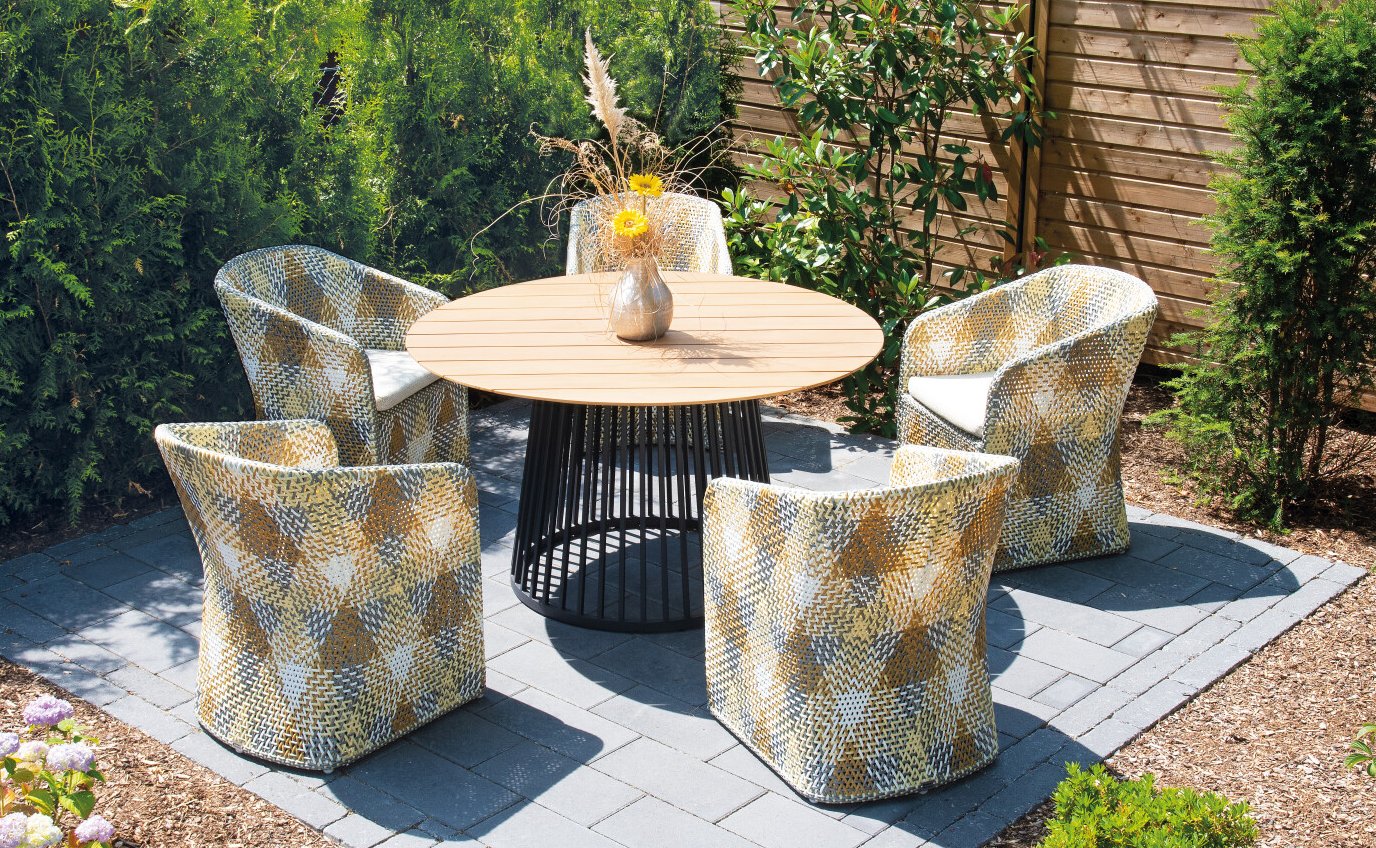 Komfortabler Geflecht-Sessel und robuster Gartentisch mit runder Teakholz-Tischplatte